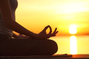 Woman seated with mudra at sun rise for a guide for setting intentions for personal fulfillment 