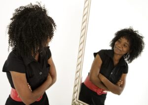 A woman looks at herself in the mirror for her self-concept or sense of self, which differs from self-identity