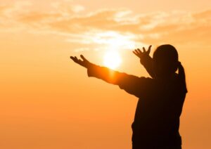 Woman reaching for sunlight for spiritual connection and the chakras